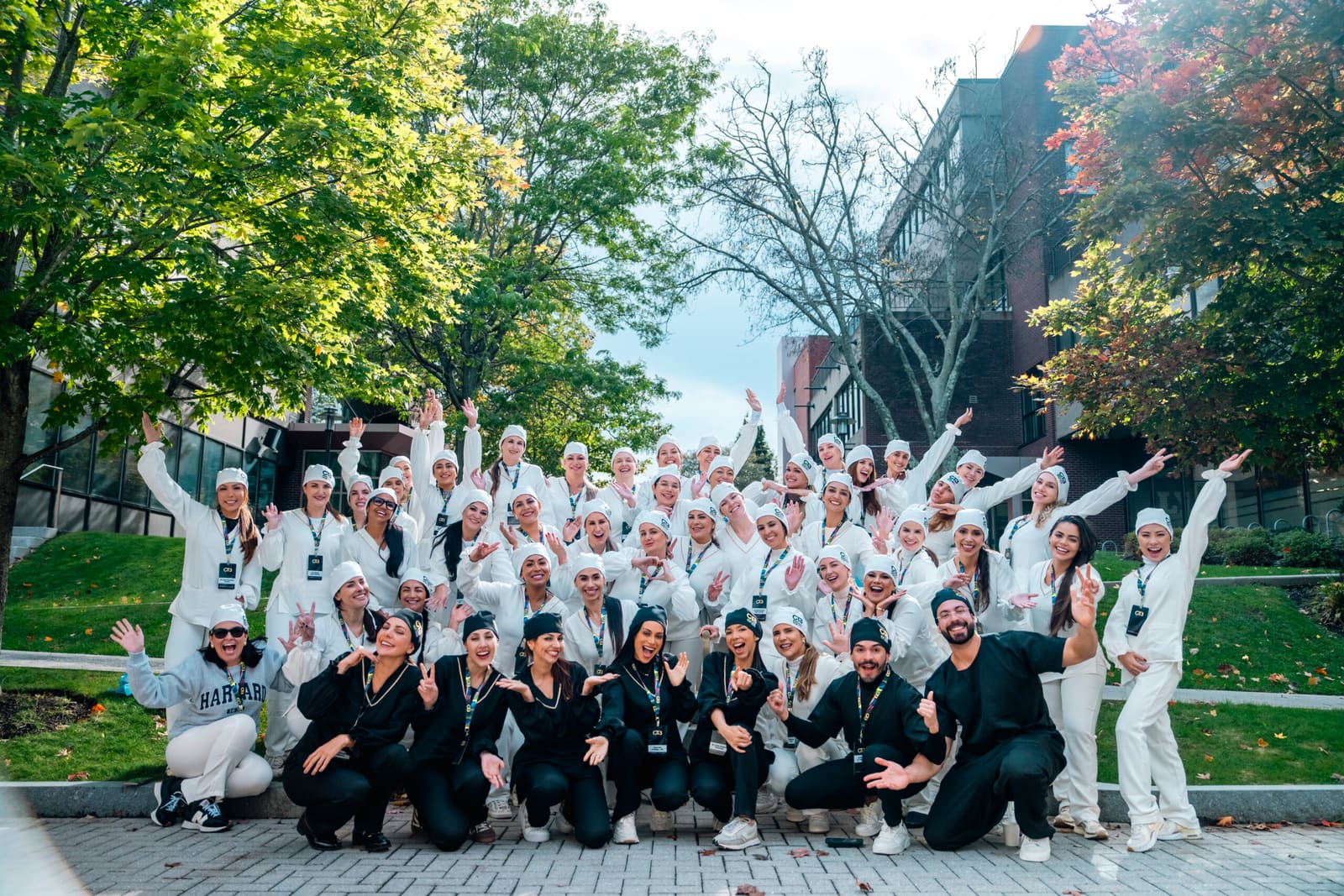 Turma do OTB reunida ao ar livre no campus em Boston, com a paisagem acadêmica ao fundo.